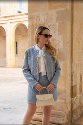 a lady in a white bow tie neck shirt and a blue tweed suit